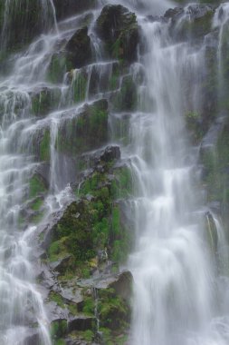 Doğal bir şelale uçurumdan akan bir vadiye doğru uzun bir hat çizer..