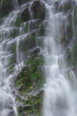 Doğal bir şelale uçurumdan akan bir vadiye doğru uzun bir hat çizer..