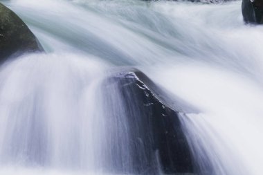 Doğal bir şelale uçurumdan akan bir vadiye doğru uzun bir hat çizer..