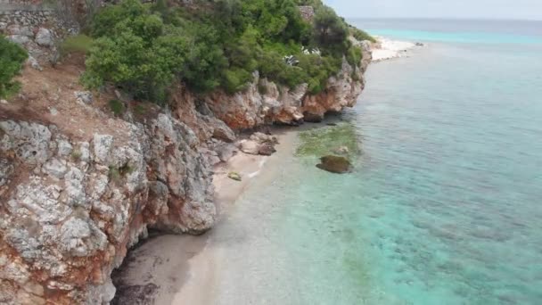 野生のビーチ ターコイズ ブルー エメラルドの透明な水のように澄んだ海の岩の崖の空中ドローン ビュー — ストック動画