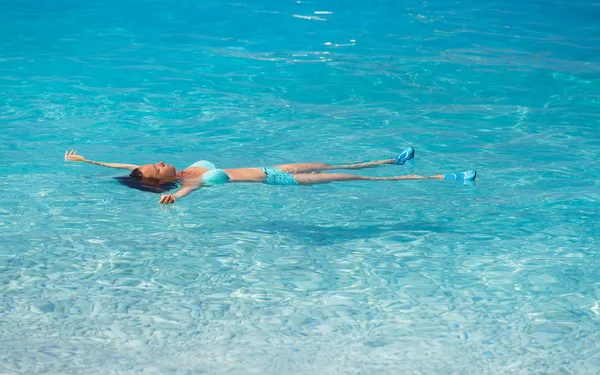 Beautiful woman floating in the ocean water and relaxing