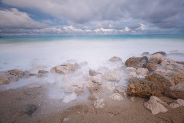 Fırtınalı gökyüzü, uzun pozlama görüntü altında kayalık bir plajda gelen gelgit 