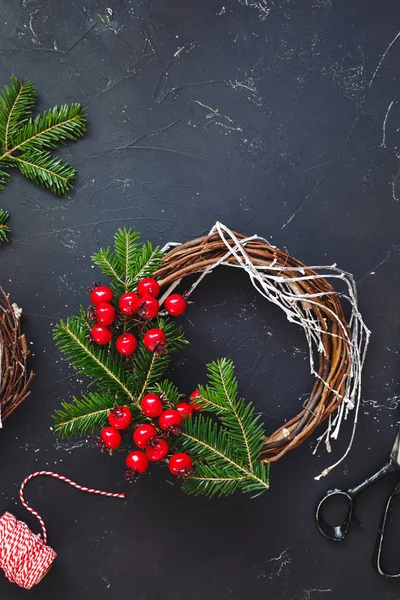 质朴的圣诞葡萄藤花圈用品 手工制作的圣诞花环装饰与天然云杉树枝在黑暗 质朴的表面 — 图库照片