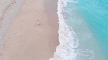 Dalgalar arasında tropikal kumlu plajda yürüyüşe yalnız kadın