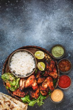 Dumanlı, kavrulmuş tandoori kanatları ile pilav pirinç, yumuşak sarımsak peynir naan farklı Hint turşusu daldırma sos ile servis tavuk. Üstten görünüm, boşluk, rustik arka plan