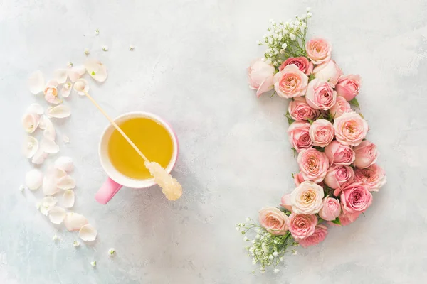 Cup of tea with roses and petals frame. Flat lay of rose flowers , petals and cup of tea over textured background