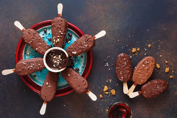 Chocolate covered ice cream sticks with milk and dark chocolate on rustic background. Top view, blank space