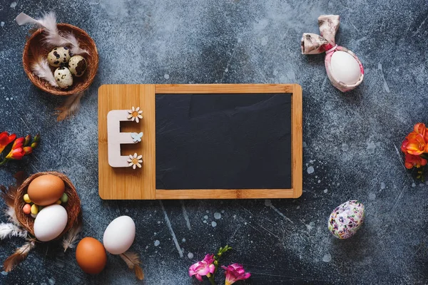 Easter letter E with different  quail and chicken eggs on rustic background. Top view, blank space