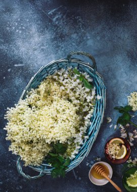 Gözlük ve sepet içinde mürver çiçeği şurubu rustik masada mürver çiçekleri ve akasya taze çiçekleri ile. Üst görünüm, boş alan