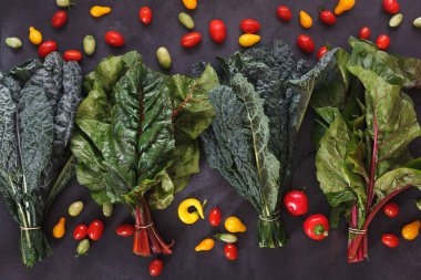 Taze yapraklı yeşillik, kiraz domates ve rustik yüzeyde biber. Çiftçi pazarı, diyet ve beslenme konsepti. Üst görünüm, boş alan, düz döşeme