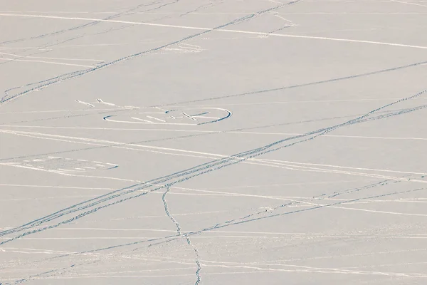 Human traces and traces of animals in the snow on a frozen river