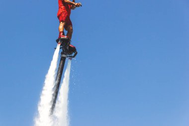 Uçan tahta, kırmızı bir Flyboard adam, mavi gökyüzüne karşı