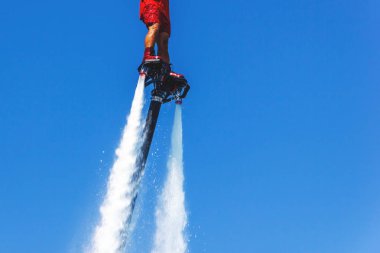 Uçan tahta, kırmızı bir Flyboard adam, mavi gökyüzüne karşı