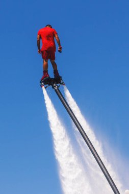 Uçan tahta, kırmızı bir Flyboard adam, mavi gökyüzüne karşı