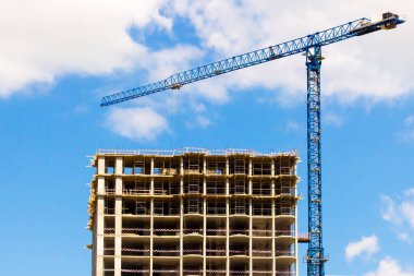 Mavi gökyüzüne karşı modern monolitik yapı. Monolitik apartman inşaatı sırasında tek bir inşaat kulesi vinci..