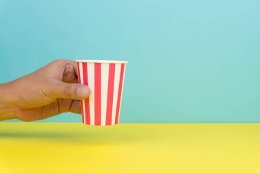 bir renkli parti kağıt bardak, sarı ve mavi arka plan tutan el