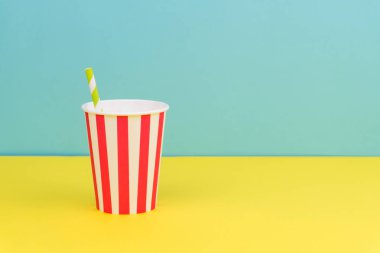 mavi arka plan ile sarı tabloda yeşil şeritli saman ile çizgili parti kağıt bardak