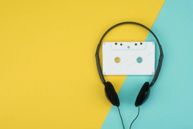 bir beyaz ses Kaset siyah bir kulak içi kulaklık ile üst görünümden sarı ve mavi arka plan üzerinde