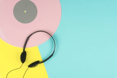 sarı ve mavi arka plan üzerinde siyah bir kulak içi kulaklık ile pembe uzun yürütme vinil kaydetme veya Lp üstten görünüm