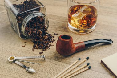 Tütün kavanoz, boru dış müdahale aracı, maçlar ve bir bardak viski ahşap masa üzerinde yasaktır boruyla