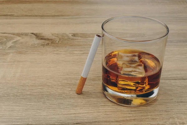 一杯波旁威士忌 冰块和一支香烟放在木桌上 — 图库照片
