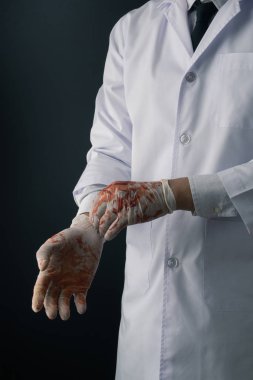 Beyaz önlük koyu arka plan üzerinde kanlı lateks eldiven giymiş bir doktor