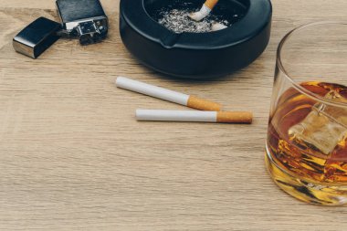 bourbon viski, Sigara, metalik çakmak ve siyah seramik kül tablası ile sigara külleri tam bir bardak ahşap masaya butts