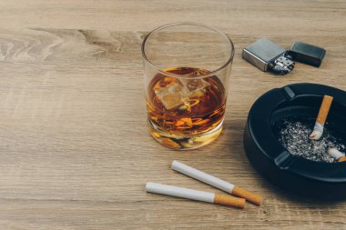 bourbon viski, Sigara, metalik çakmak ve siyah seramik kül tablası ile sigara külleri tam bir bardak ahşap masaya butts
