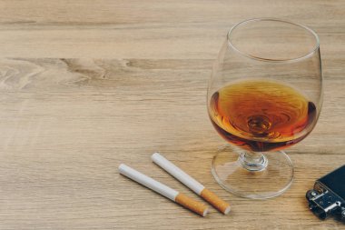 bir bardak konyak, Sigara ve Metalik ahşap masaya hafif