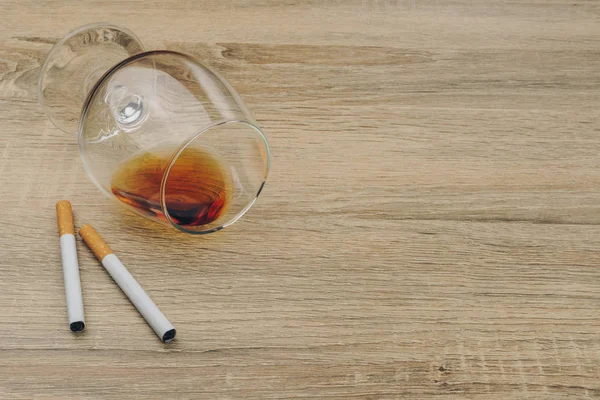 一杯白兰地和香烟在木桌上 — 图库照片