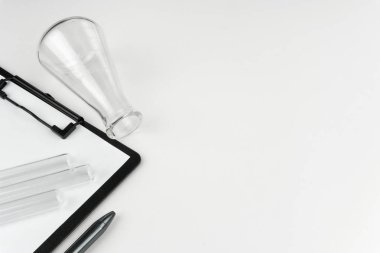 laboratuvar aletleri. Bir şişesi, test tüpleri, pano ve beyaz masanın üzerine kalem