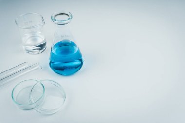 laboratuvar aletleri. Mavi bir sıvı şişesi, test tüpleri, petri kabına ve beyaz tablo tarih temiz sıvı kabı