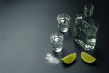 bir şişe iki tekila shot gözlüklü gümüş tekila kireç dilimleri ve masada tuz