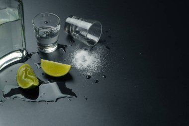 bir şişe tekilayla gümüş tekila gözlük ve kireç dilimleri ile tuz ıslak masaya vurdu