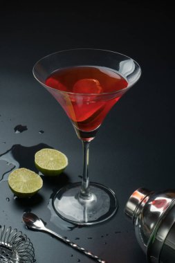 Cosmopolitan kokteyl ve aletleri, paslanmaz çelik kokteyl shaker ve bar kaşığı, süzgeç ve masanın üzerine limon