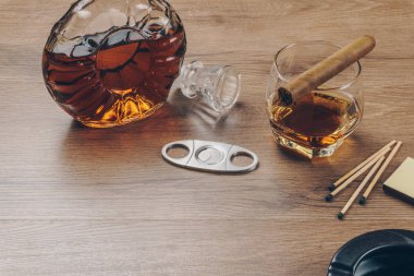 Bourbon viski, viski sürahi bir paslanmaz çelik puro kesici, maçlar ve ahşap masa üzerinde siyah seramik küllük bir bardak üzerinde Küba purosu