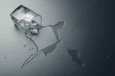 masanın üzerine dökülen buz küpleri ile bir bardak su yakın çekim