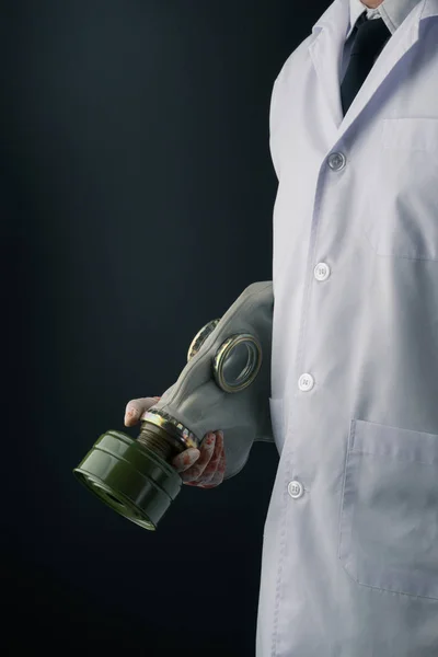 流血ラテックス手袋を着用し 暗い背景にゴム製防毒マスクを保持している白衣の医者 — ストック写真