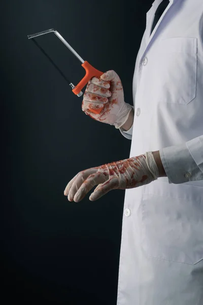 Médico Vestindo Luvas Sangrentas Com Uma Serra Mão Fundo Escuro Imagem De Stock