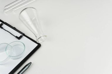 laboratuvar aletleri. Bir şişesi, test tüpleri, petri kabına ve beyaz masaya kalemiyle bir pano