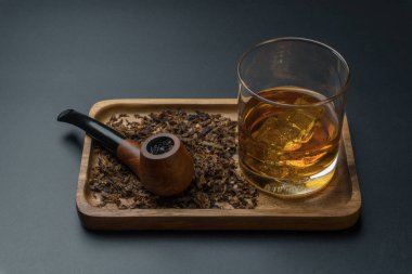 Tütün ve bir bardak burbon viski içinde ahşap tepsi, koyu arka plan yasaktır boruyla