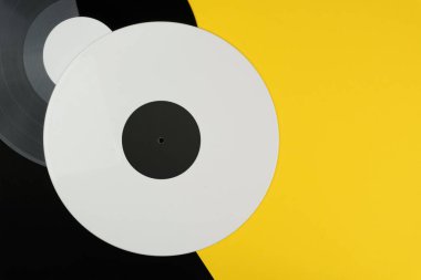 üstten görünüm bir beyaz ve bir siyah uzun oynamak vinil kayıt üzerinde siyah ve sarı arka plan