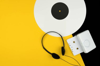 üstten görünüm beyaz uzun bir vinil kaydı, siyah kulaklık ve bir beyaz ses Kaset beyaz bir taşınabilir kaset çalar ile sarı ve siyah arka plan üzerinde oynamak