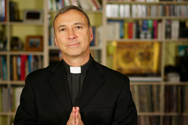  Красивый католический священник молится в своей библиотеке. Он смотрит на нас с безмятежностью, оптимизмом, радостью, восхищением, доверием, уверенностью и миром.
.