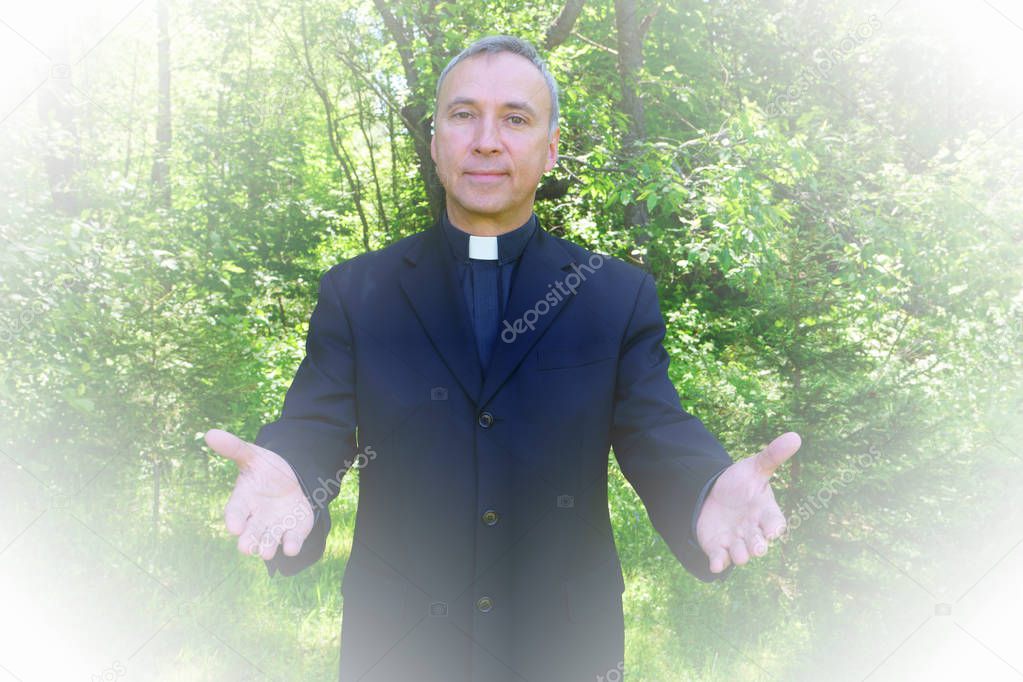 A good looking catholic priest is welcoming us in joy. He looks at us with confidence, openning his arms in peace.