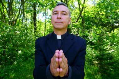 İyi görünümlü bir Katolik rahip bizimle sevinç içinde dua ediyor. Bize güven ile bakar açılış kollarını huzur içinde. Yüzünde odaklanmak.