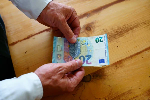 Ein Kaukasischer Mann Zählt Sein Geld Auf Dem Küchentisch lizenzfreie Stockbilder