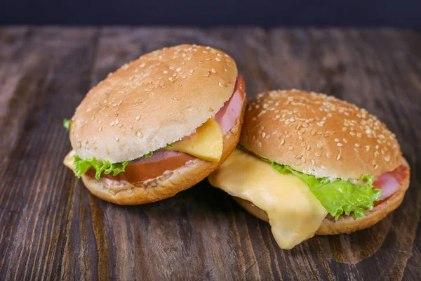 Hambúrguer com salsicha e queijo com alface fresca sobre fundo de madeira. Fechar — Fotografia de Stock