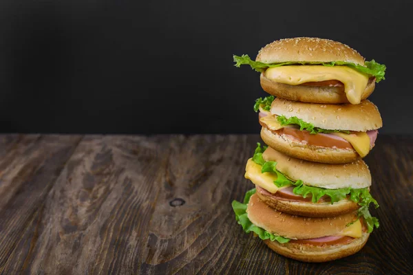 Uma pilha muito alta de cheeseburgers sobre fundo de madeira — Fotografia de Stock