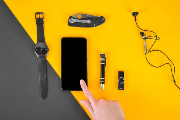 Верхний вид аксессуаров случайных мужчин на желтом и черном фоне. Мобильный телефон, часы, нож, ручка . — стоковое фото